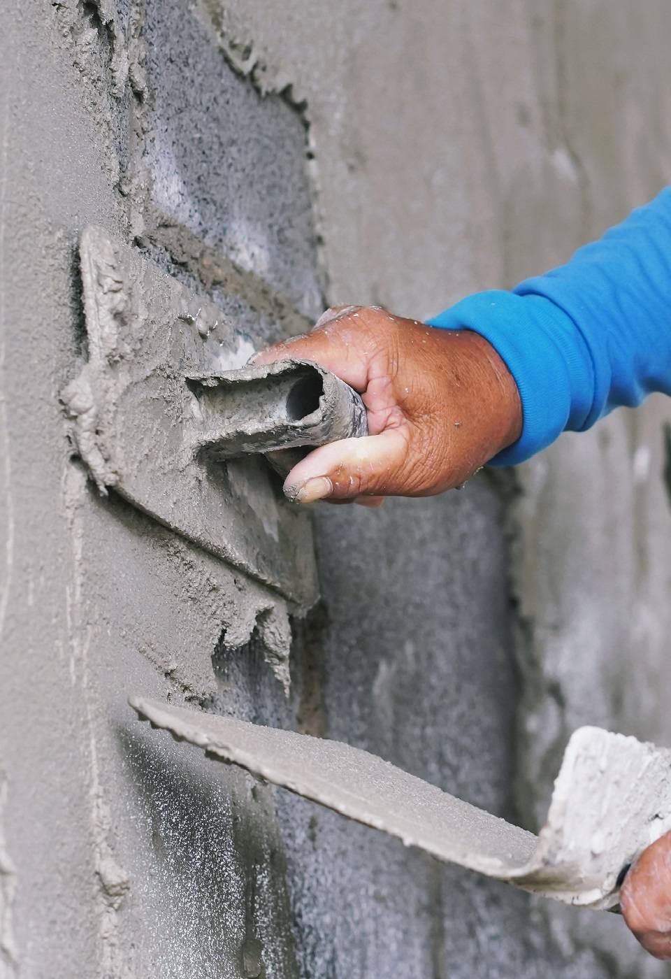hand of worker plastering cement on wall