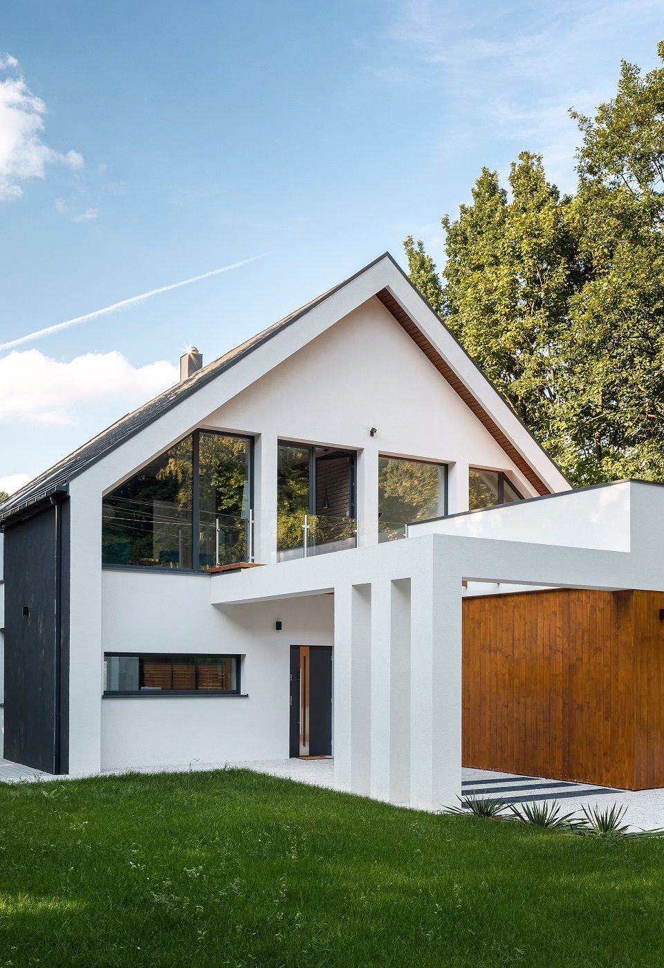 Exterior view of modern, white house with garage decorated with wood